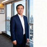 50岁企业人力资源总监周明辉的职业照，穿着深蓝色西装，站在办公室落地窗前，表情稳重大气
